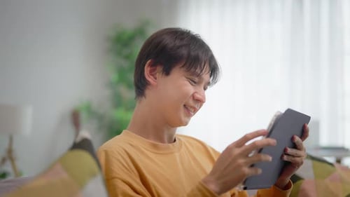 Smiling Young Adult Uses Tablet at Home