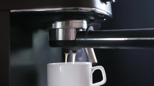 Home Espresso Making Process Coffee Stream Pouring From Machine Into Ceramic Cup