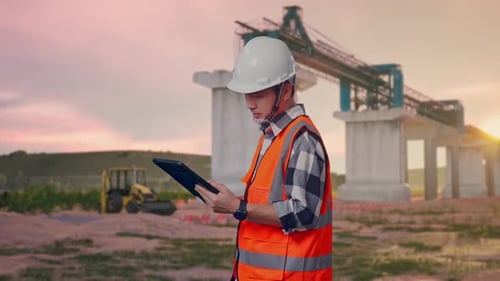 Side View Of Asian Male Engineer Working On A Tablet at Construction Site