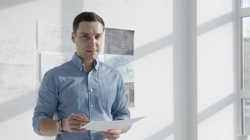 Man Architect in Sunny Office with Drawings in Hand Portrait