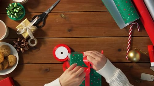 Hands Tying Red Ribbon on Christmas Present
