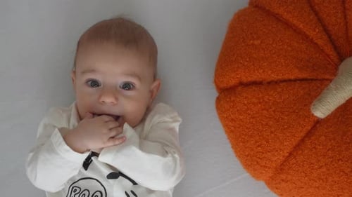 Cute Infant Lying Next to Decorative Pumpkin