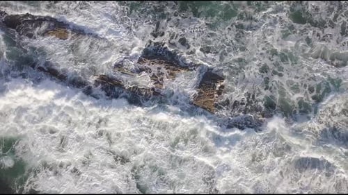 Aerial view to ocean waves with the waves crashing on the rocks