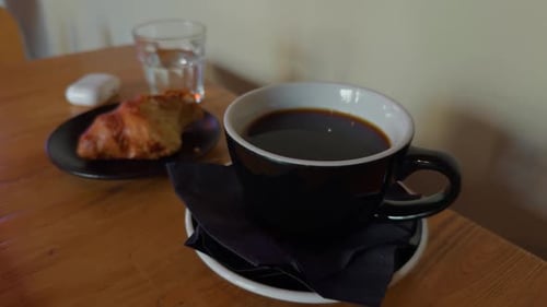 Cup of coffee with croissant on table