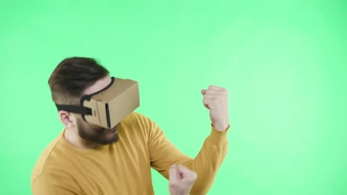 Spectacled gamer immersed in virtual reality fighting in green screen studio