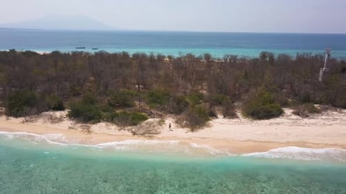 Solitary Man on Sandy Beach of Exotic Uninhabited Island, Pull Back Aerial Revealing Whole Coast, Tu