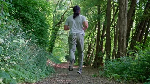 A Man Jogging Energetically Along a Scenic and Picturesque Forest Path Immersed in Nature