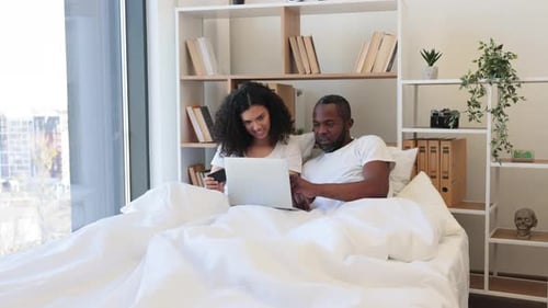 Couple Cheers Success in Bed with Laptop