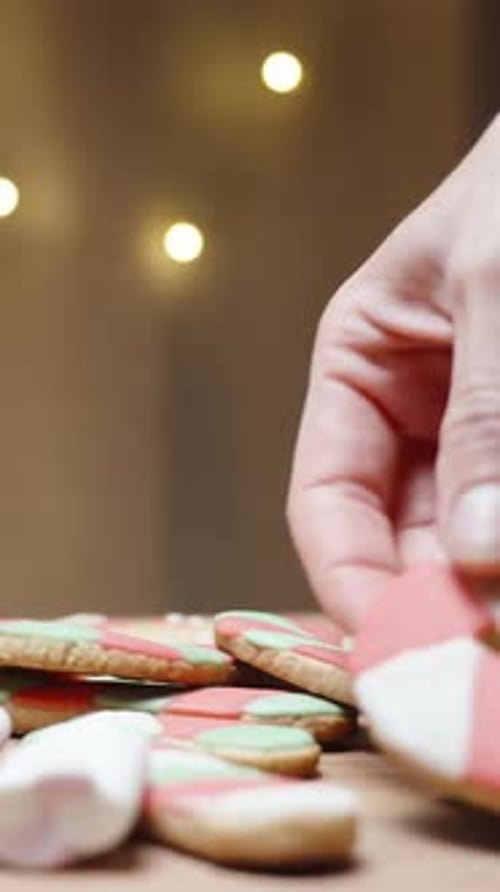 Vertical video. The woman takes a gingerbread cookie in the shape of a candy cane