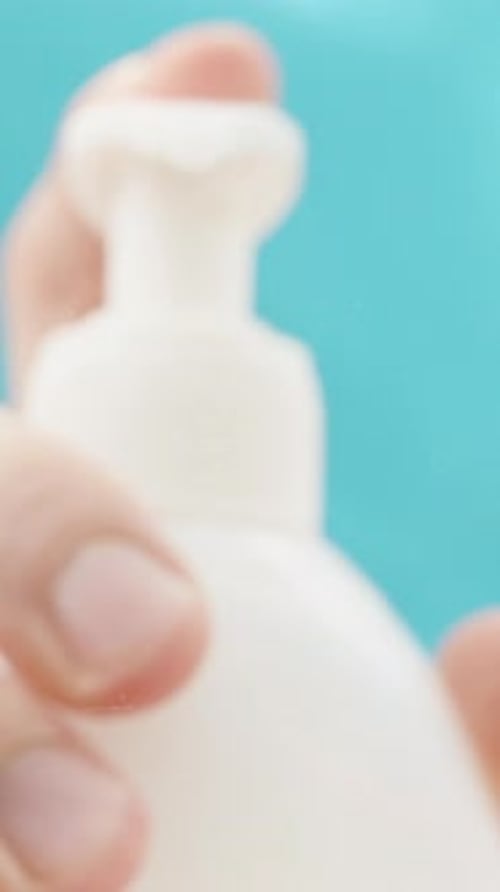 Vertical video. Low-angle view focused on the window. Squeezing liquid soap from a bottle on a blue