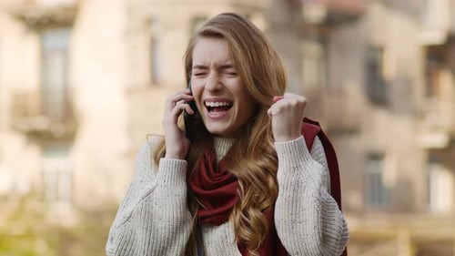 Excited woman celebrating while talking on her phone