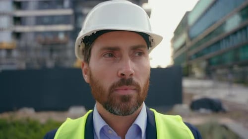 Retrato de hombre de cerca, obrero reparador con casco de seguridad mirando a su alrededor, sonriendo, hombre contratista, vistiendo