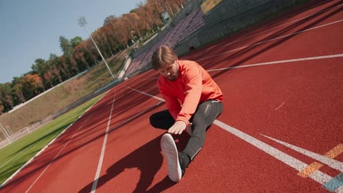 Athlete Stretching on Red Running Track on Sunny Day