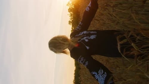 Vertical portrait happy ukrainian woman in embroidery national dress walking on a wheat field
