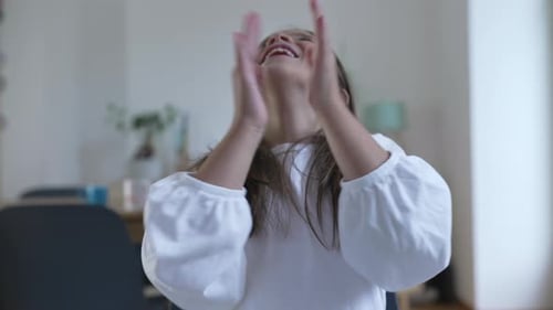 Energetic happy child clapping hands toward camera smiling. One little girl celebrating success and