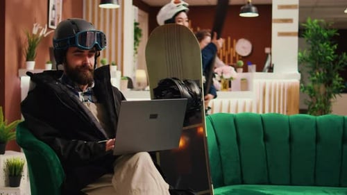 Man in Helmet Using Laptop in Hotel Lobby