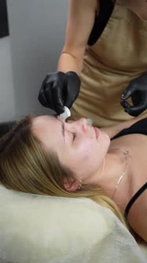 Hair removal master applies wax on client's face. Eyebrow correction with wax. Close up