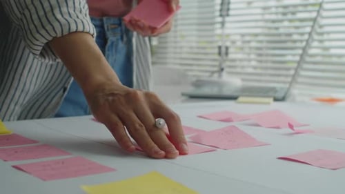 Woman Writes on Sticky Notes During Brainstorming Session