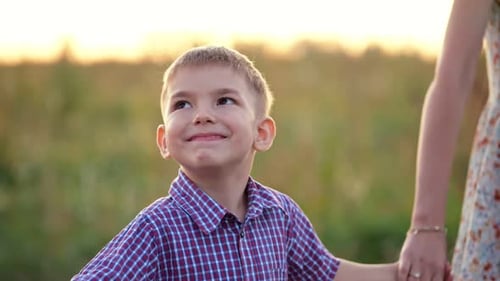 Un garçon d'âge préscolaire heureux passe devant un champ de blé avec ses parents