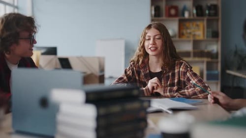 Junge Studentin spricht und lacht mit Freunden in der Bibliothek