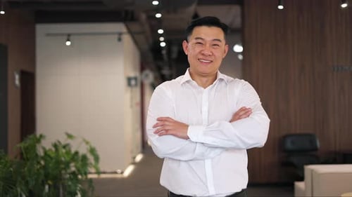 Man smiling with arms crossed in office