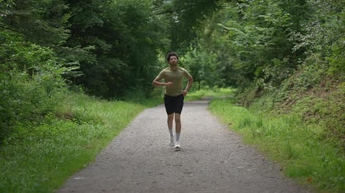 A Man is Enthusiastically Running on a Beautiful Scenic Trail Surrounded By Lush Nature