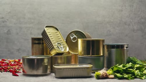 Latas de metal con comida enlatada o paté sobre la mesa, primer plano, latas doradas y plateadas con anillos de tracción enlatadas