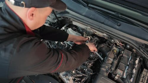 A Car Repairman Repairs a Passenger Car Engine