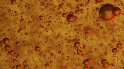 Iluminação vermelha refletindo através de um líquido em um número infinito de bolhas de sabão