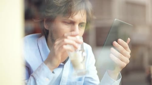 4k video footage of a young businessman using a digital tablet while working in a cafe