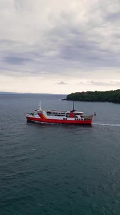 Eine einzelne Fähre segelt über das offene Meer in der Nähe von Padang Bai Bali, aufgenommen in einer atemberaubenden Luftaufnahme
