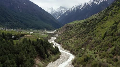 River Flowing through Serene Mountain Valley with Forested Hills