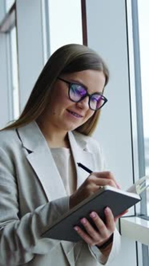 Young Woman Writing in Notebook by Window