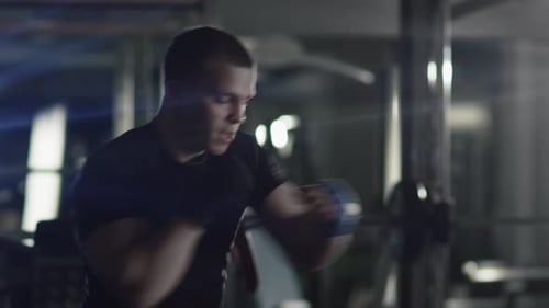 Professional male boxer is training punches and kicks in the gym.
