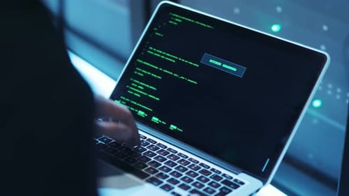 Beschäftigt sich mit fokussierter Programmierung auf einem Laptop mit dynamischer Codeanzeige auf dem Bildschirm