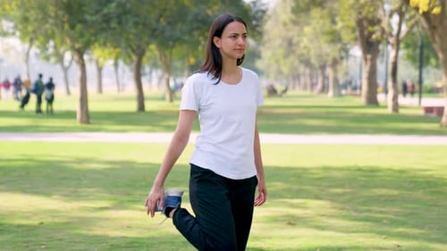 Young Woman Stretches Her Legs In the Park