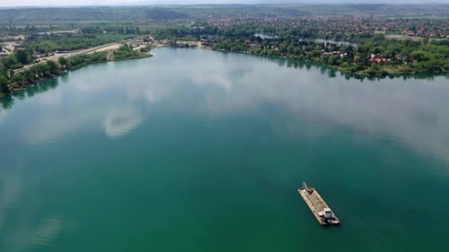 Industrial ship slowly sailing along the river with trees on the waterfront. Tisza river, Hungary