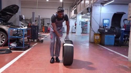 Mechanic Rolling a Tire in a Garage