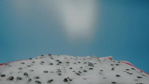 Flying over a dragon fruit (Pitaya) slice on blue background. slider zoom out with probe lens.