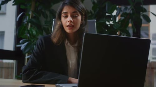Girl is Making a Video Call in the Office A Businesswoman is Talking at a Conference on a Laptop