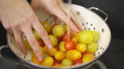 Vista de cerca de las manos Una mujer lava los tomates frescos antes de preparar una ensalada