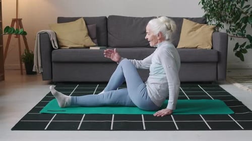 Senior Woman Exercising and Stretching on Yoga Mat