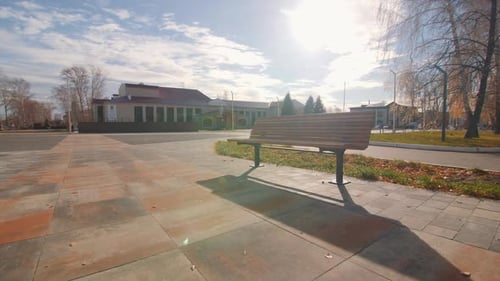 Empty Wooden Bench on Square in Urban Park in Autumn