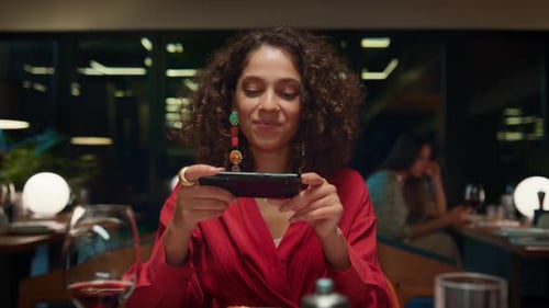 Young african american woman taking pictures of food at restaurant table on date