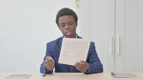 Young Adult Reads Document in Bright Office