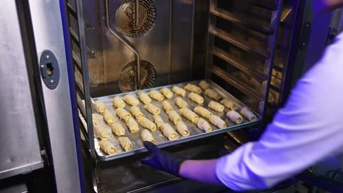 Baker Placing Pastries in Commercial Oven for Baking