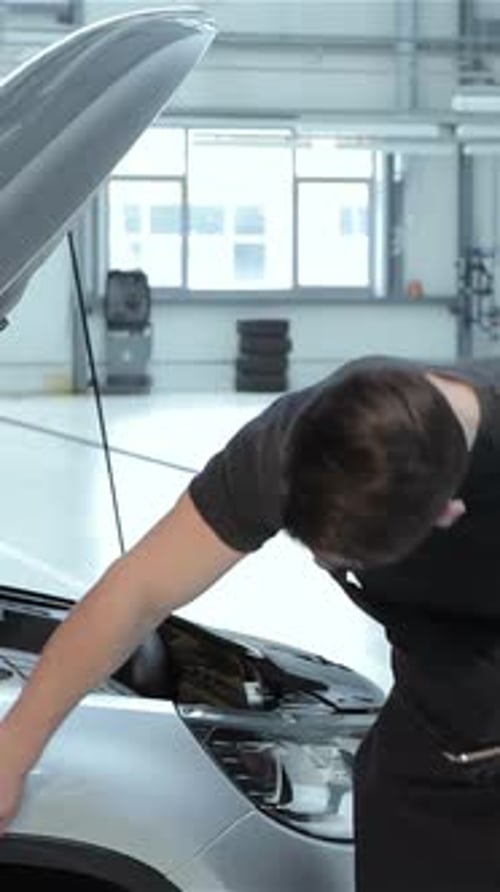 Mechanic Inspecting Car Fender with Focused Attention at the Service Station