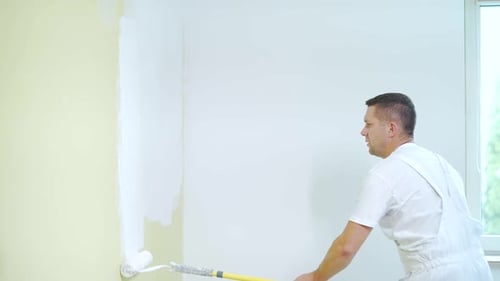 Adult Painting Wall With Long-handled Roller Indoors
