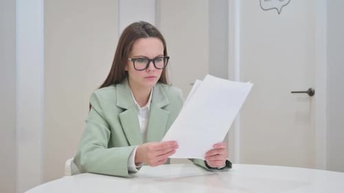 Confused woman reviews documents at white table