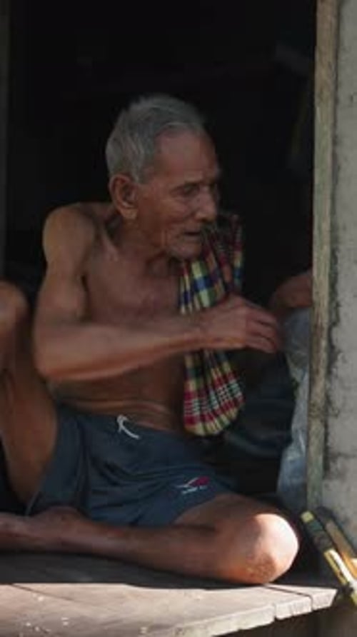 Elderly Man Sitting on Porch Steps in Doorway